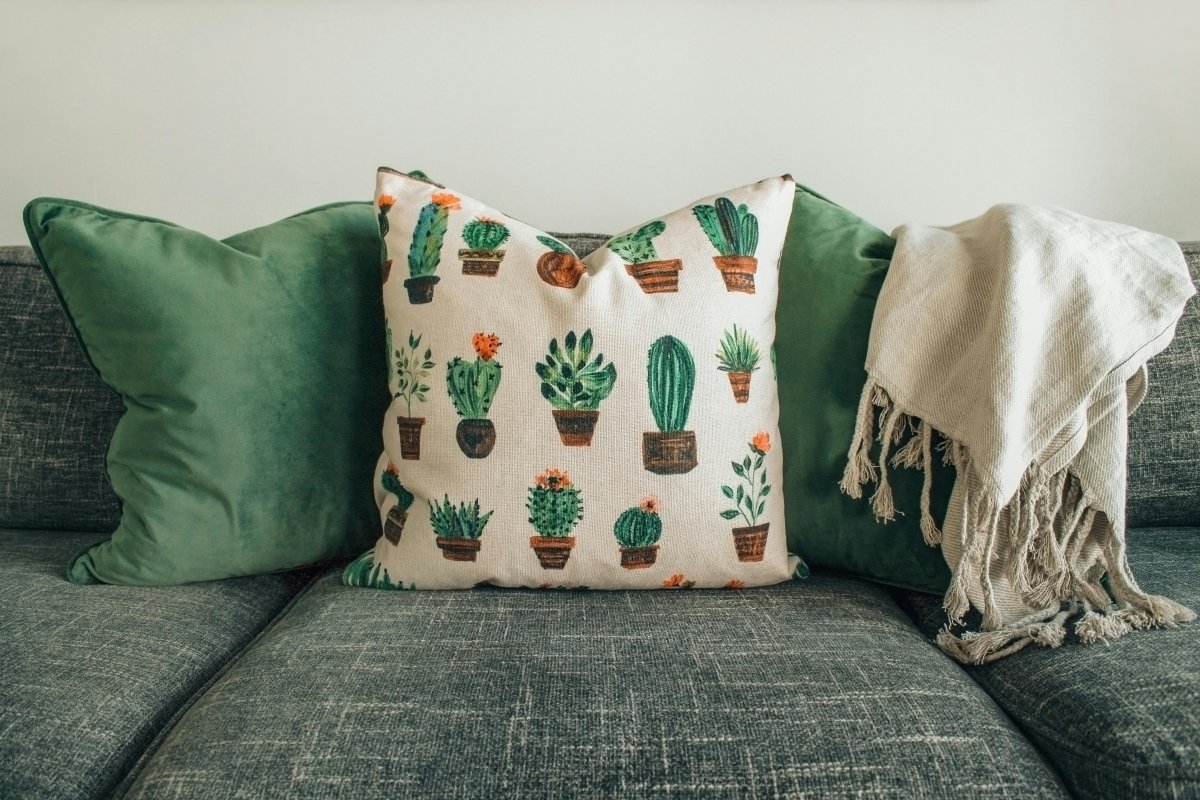 Stylish green sofa with decorative throw pillows featuring a cactus pattern.